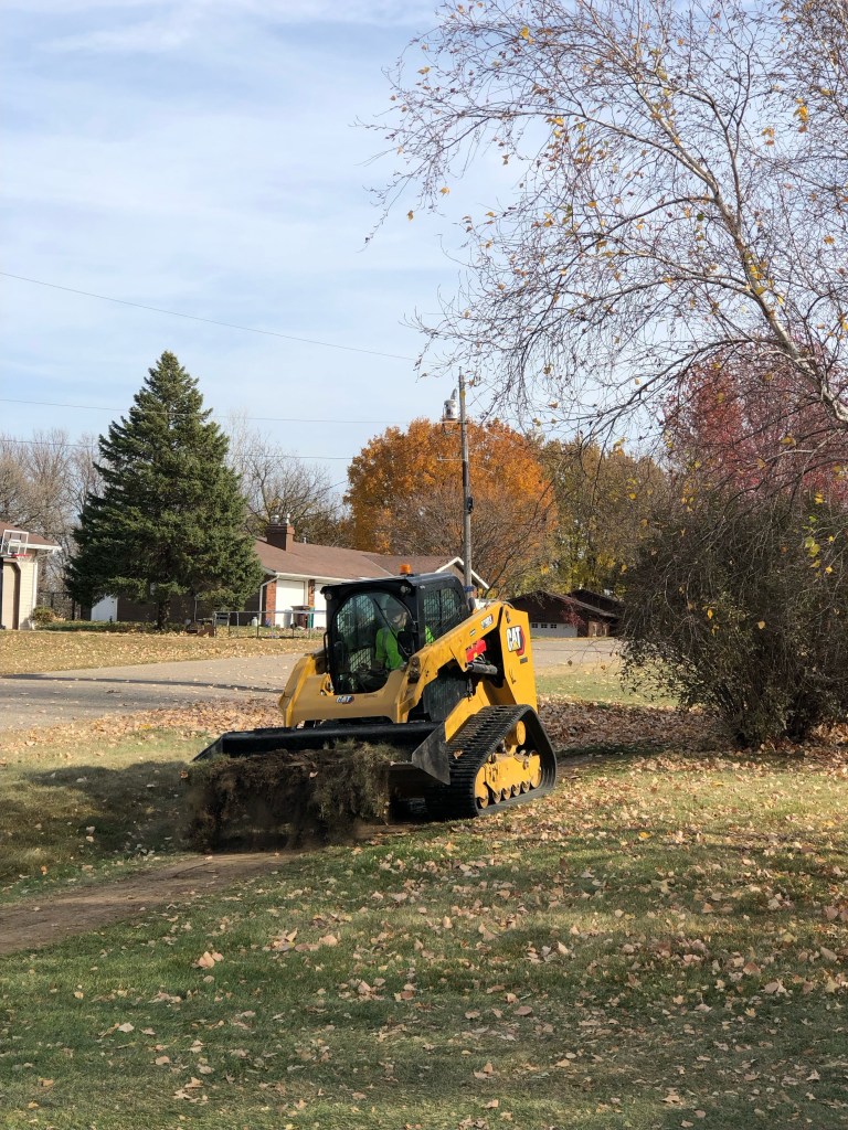 Skidsteer pushing a yard of dirt, in the process of re-sodding a front yard.